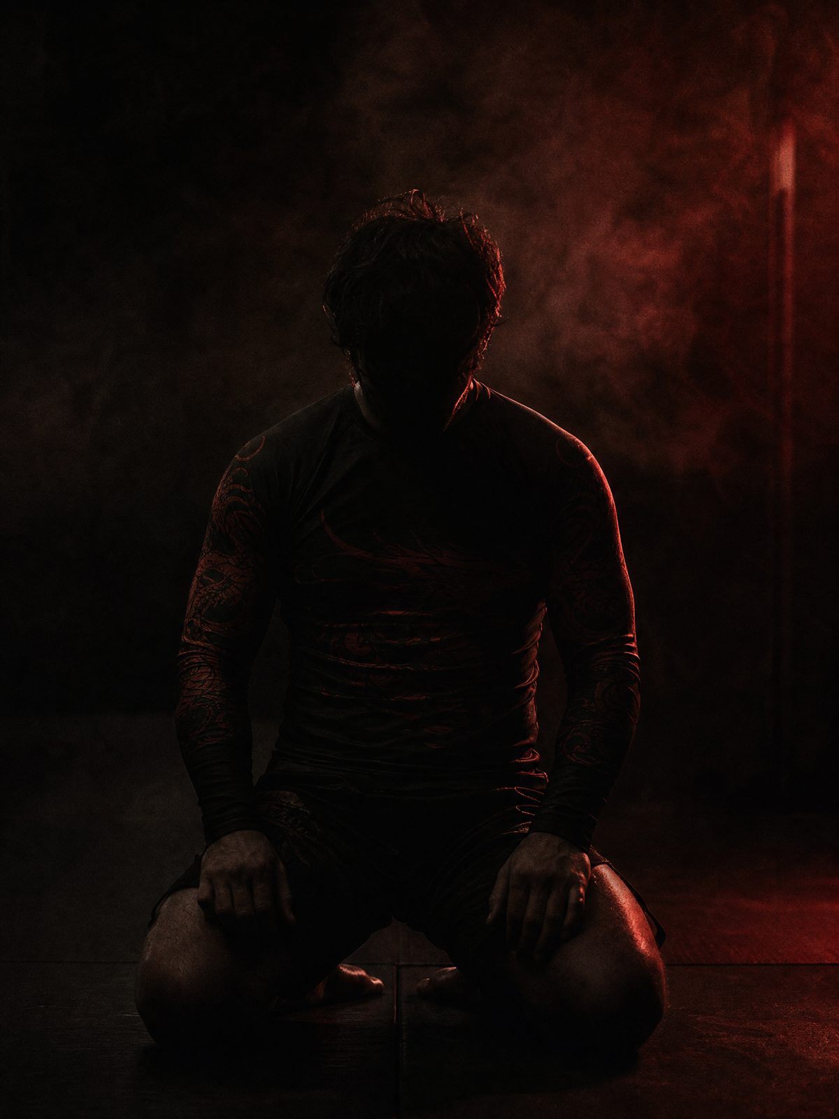 Grappler in Bloodmoon rashguard kneeling on dark mats